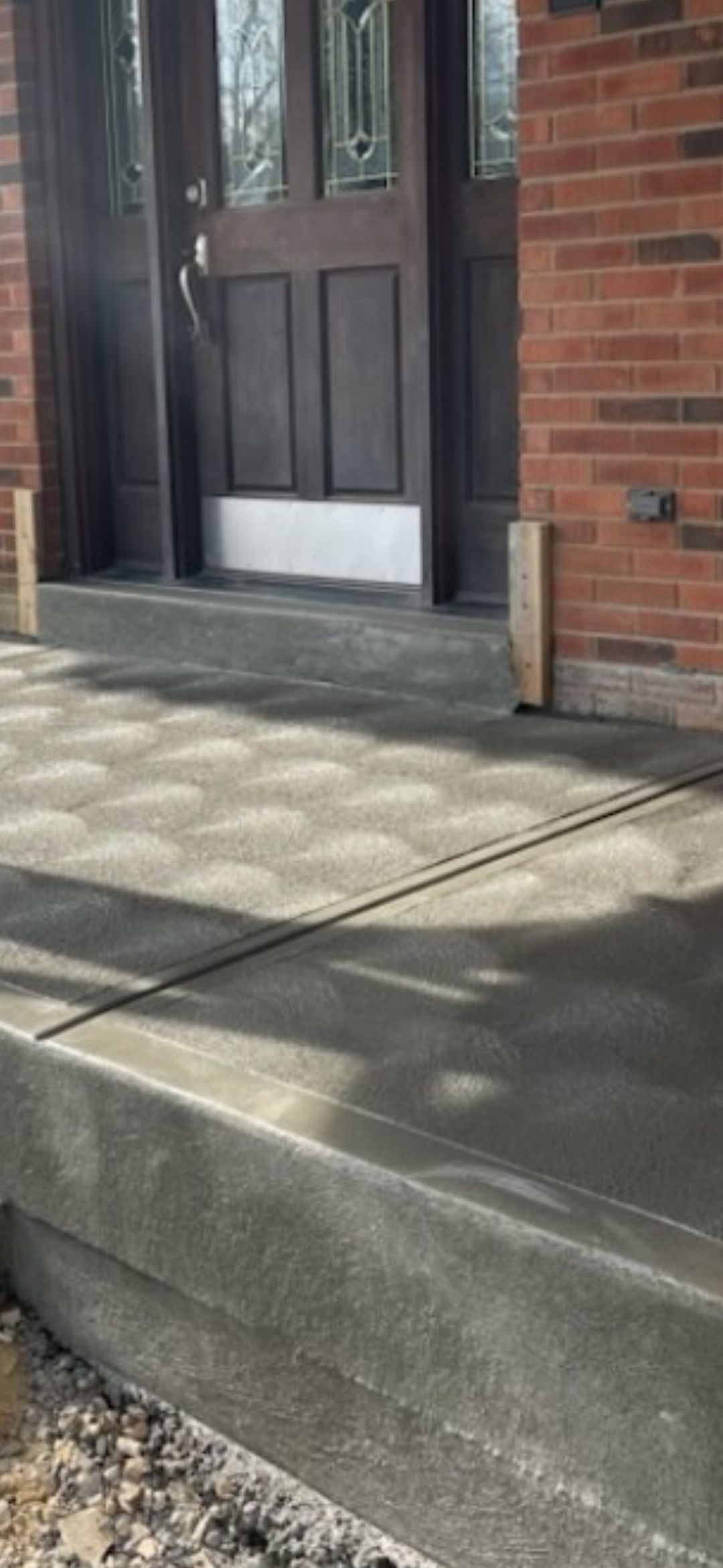 a brick building with a concrete walkway leading to the front door