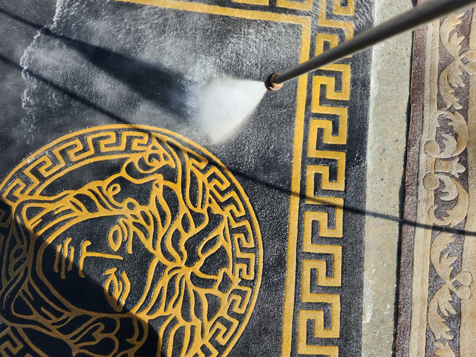 powerwashing the black and gold rug
