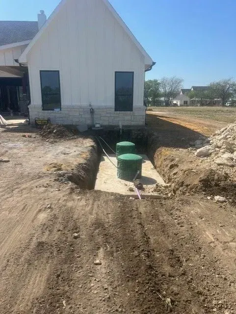 Construction site with septic tanks installed near a white house.