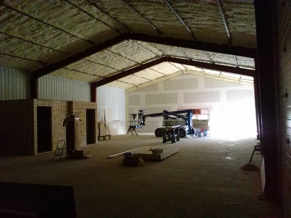 Empty warehouse interior with a truck and equipment near a bright open doorway