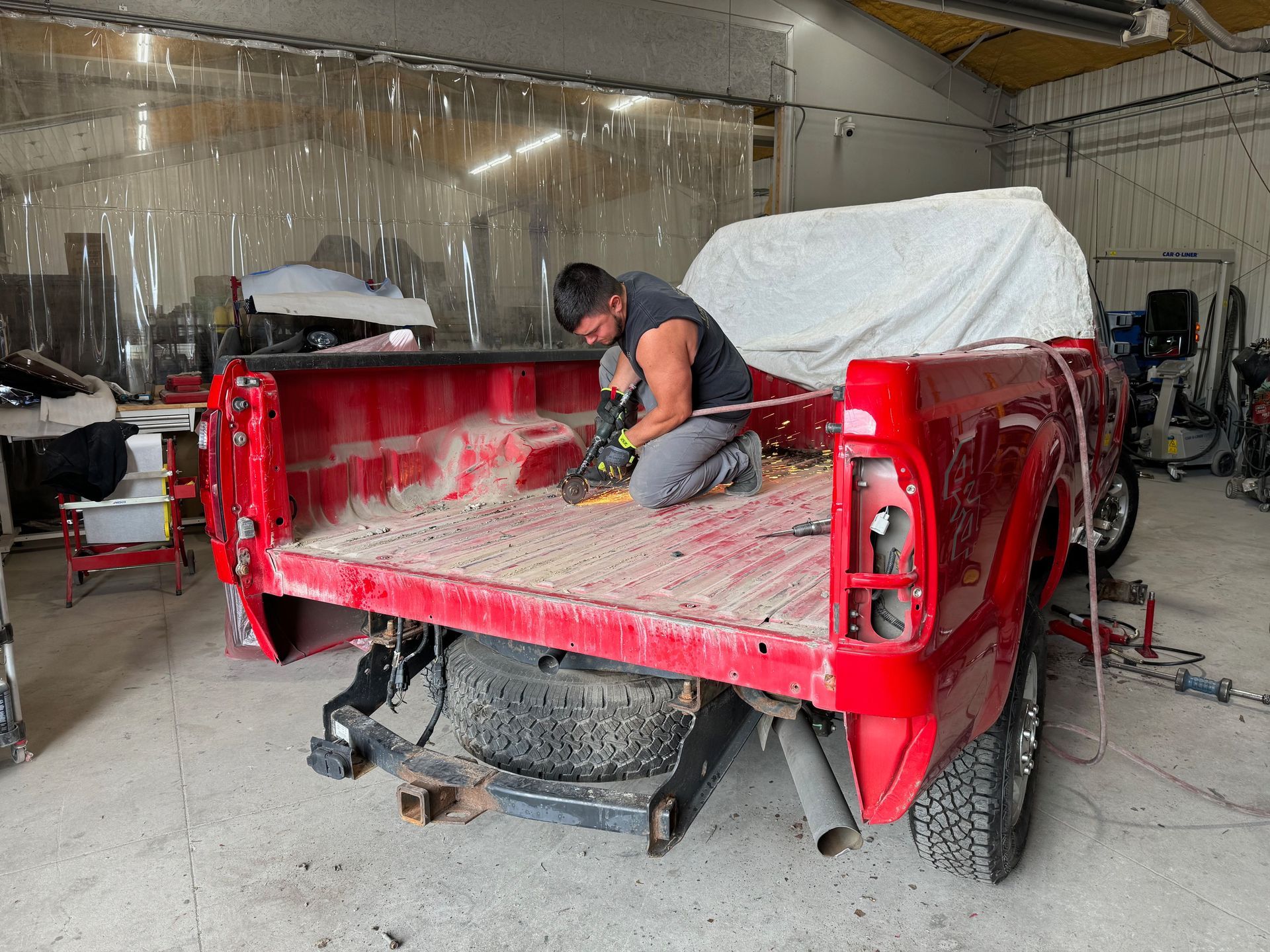 Worker grinding the red body of a vehicle frame in a workshop
