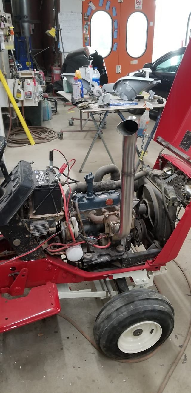 Red vehicle chassis in a garage, showing exposed engine and components during repair.