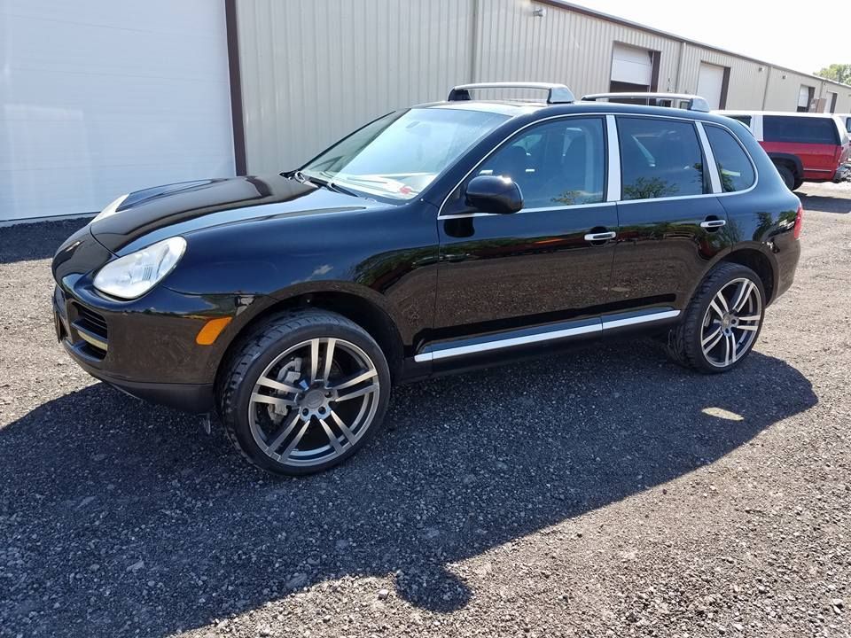 Black SUV parked outside a building on a gravel lot