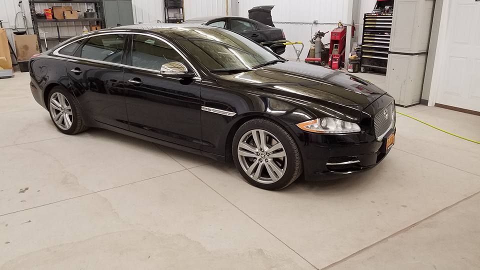Black sedan parked inside a bright garage or showroom.