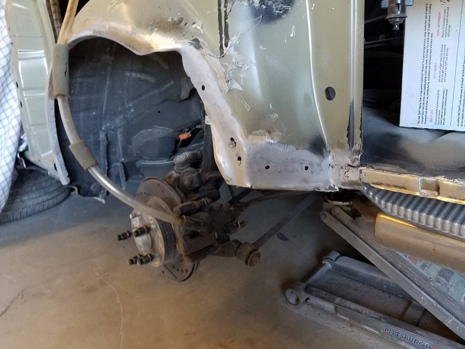 Damaged car wheel well with exposed suspension and body panel removed in a garage