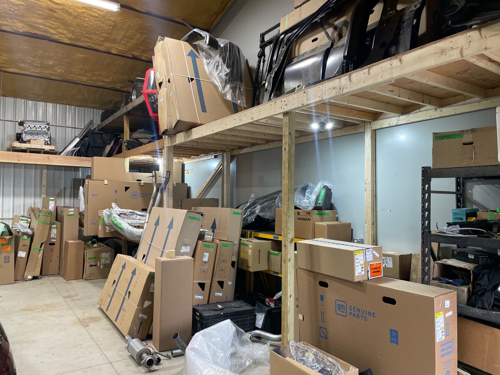 Warehouse storage area with stacked cardboard boxes and shelving under a lofted ceiling