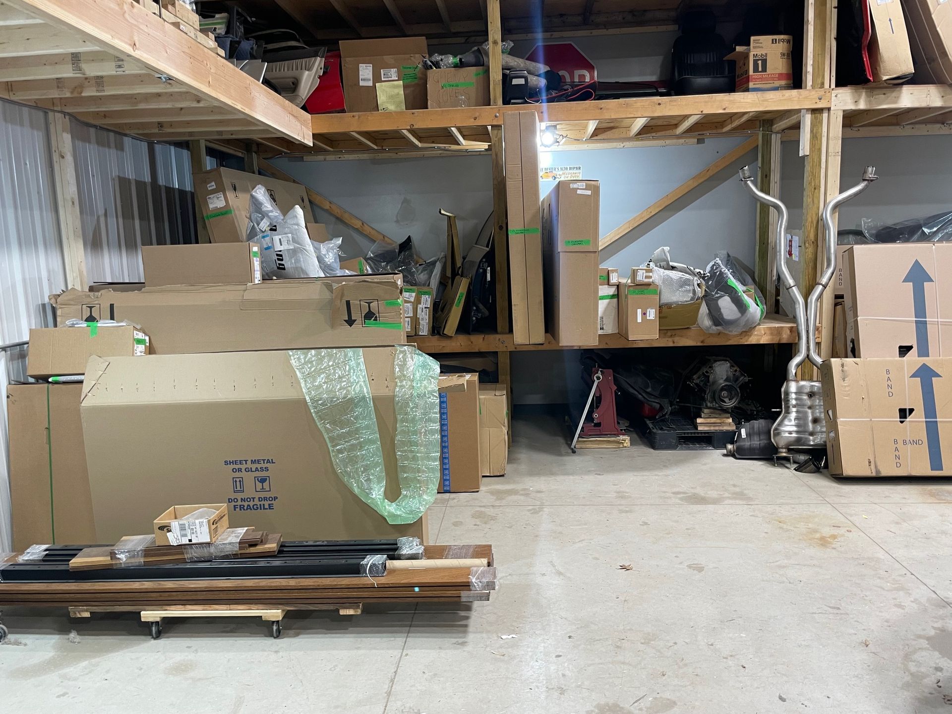 Cluttered storage room with stacked cardboard boxes, shelves, and packed items on a concrete floor.