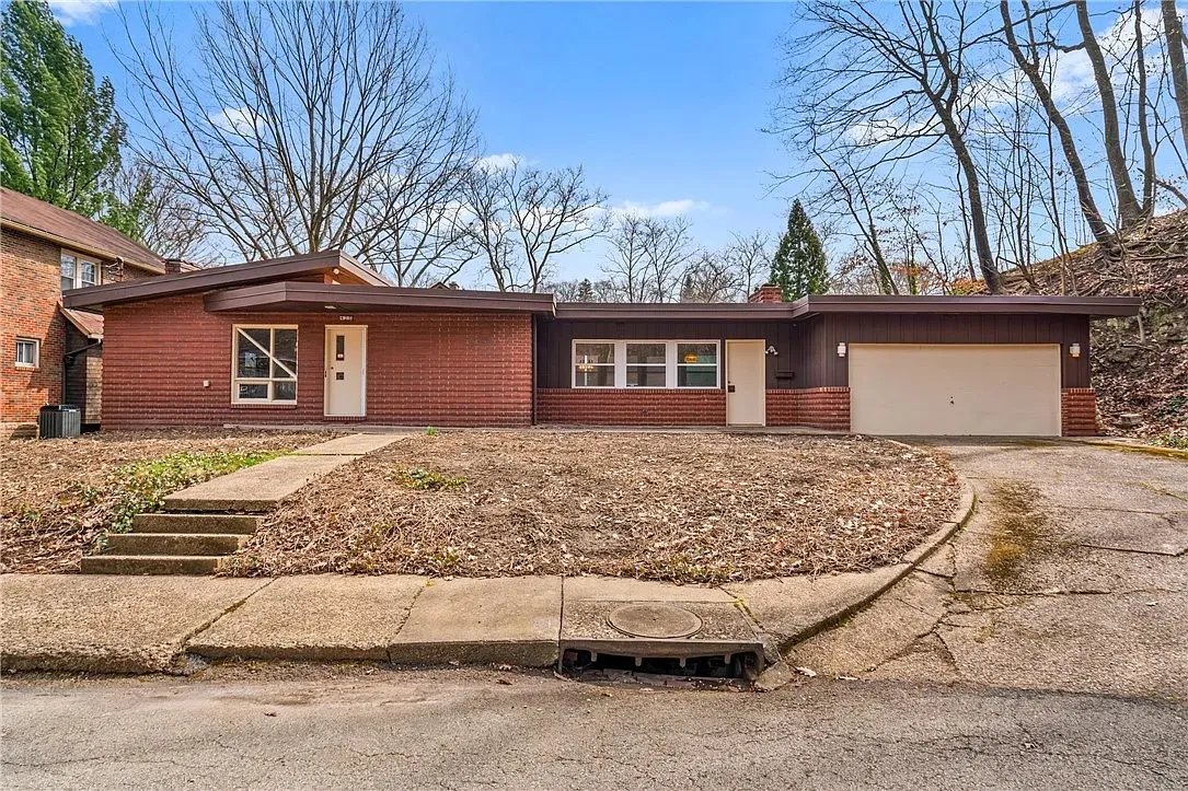 Single-story red house with garage, front steps, and leaf-covered yard on a quiet street