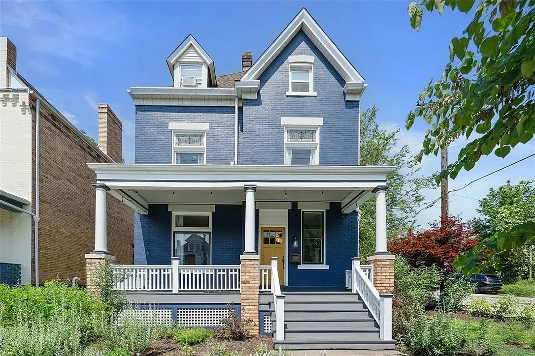 Blue Victorian house with a front porch, white trim, and steps leading to the entrance