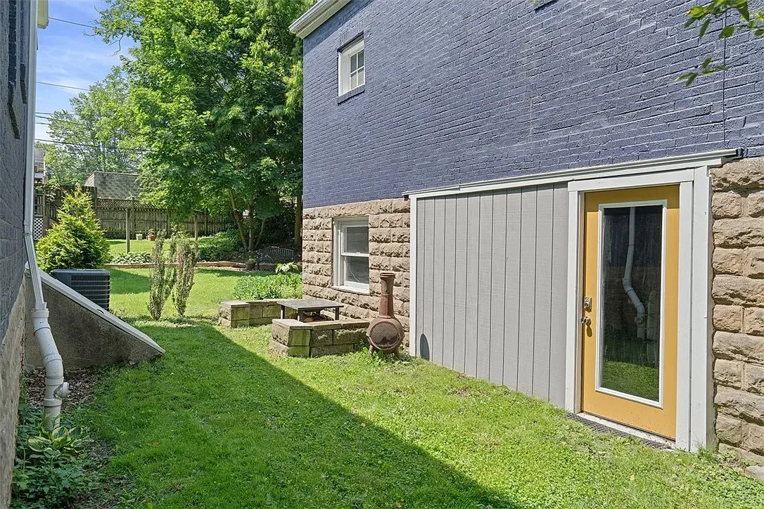 Backyard beside stone house with grass, picnic table, and sliding glass door