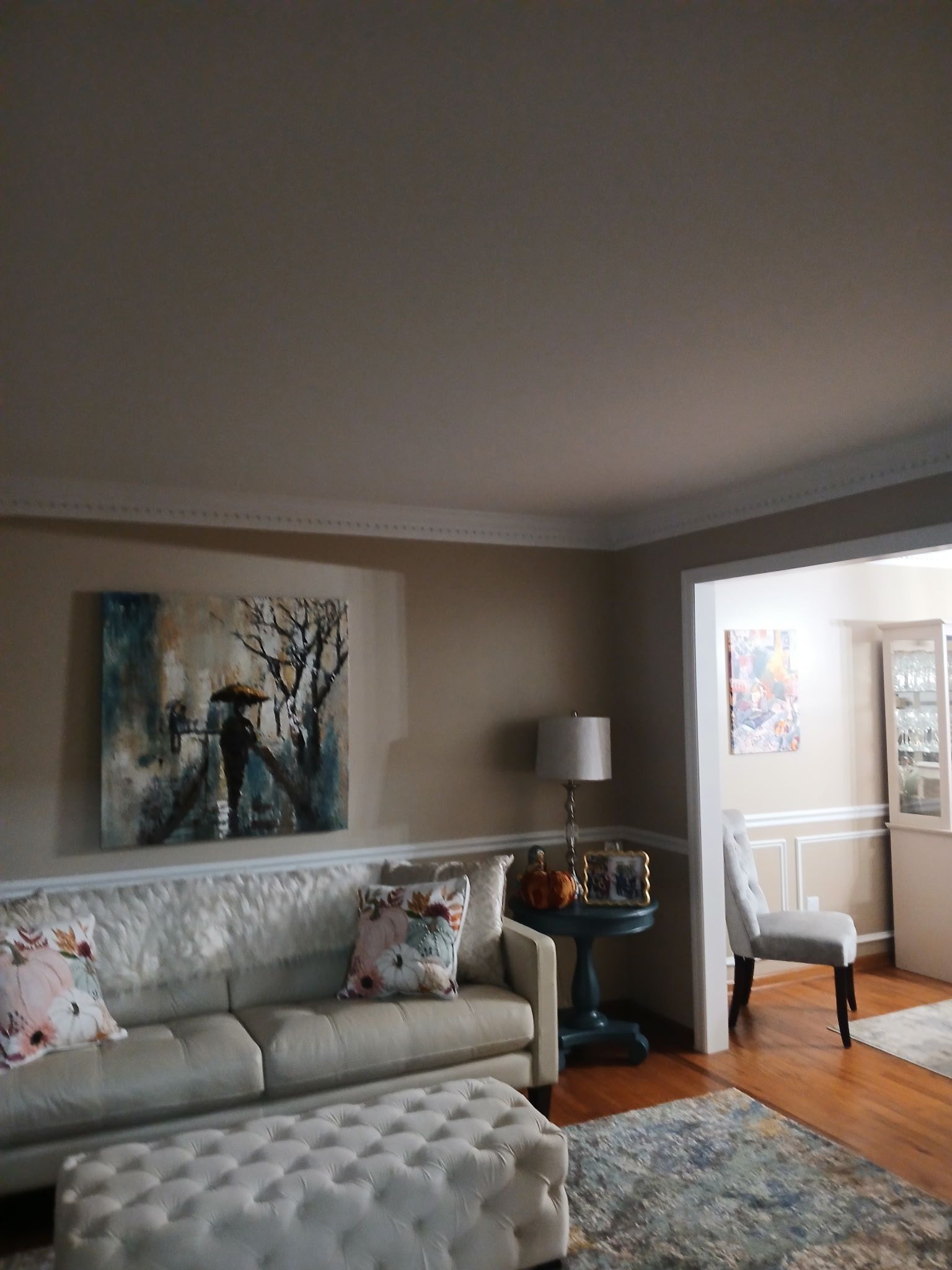 Living room with beige walls, sofa, artwork, and side table.