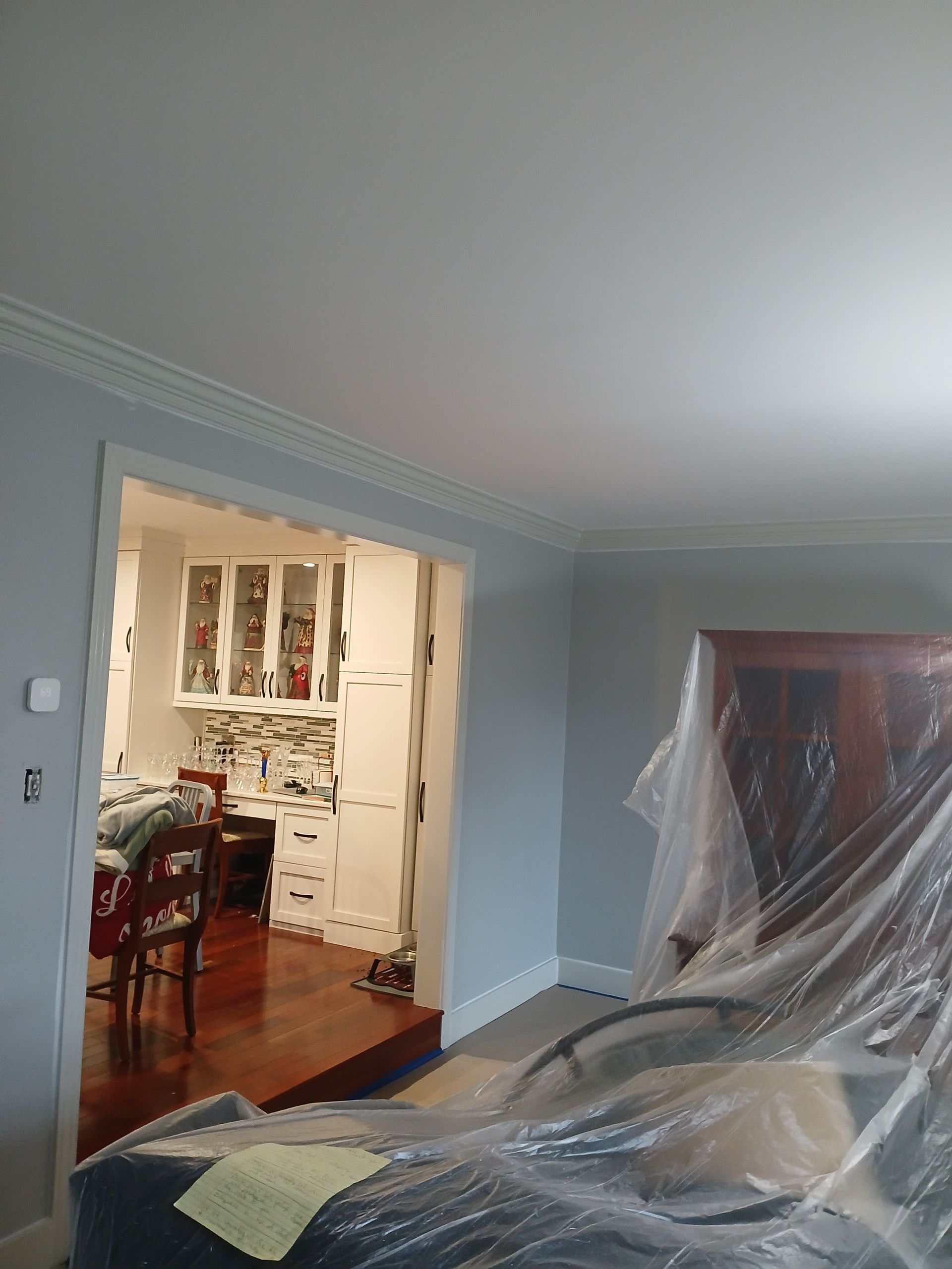 A living room with a couch and chairs covered in plastic.