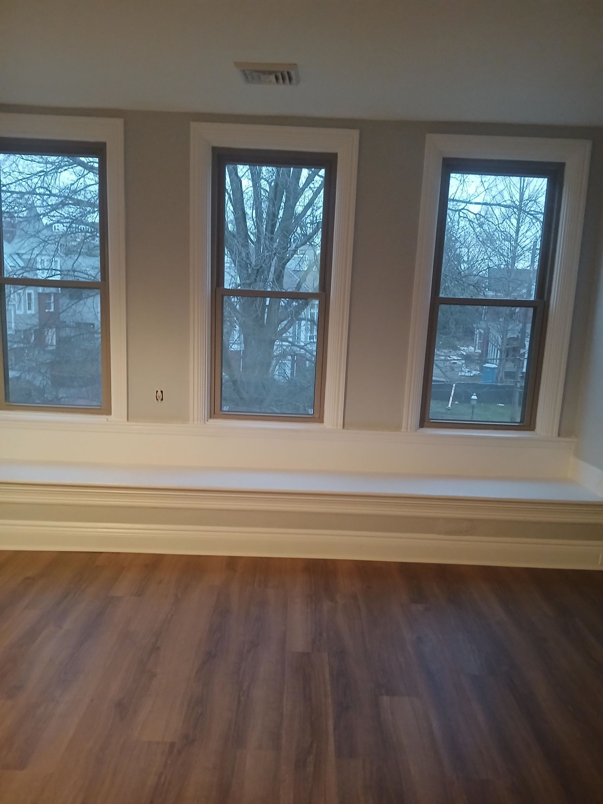 An empty room with three windows and a bench.