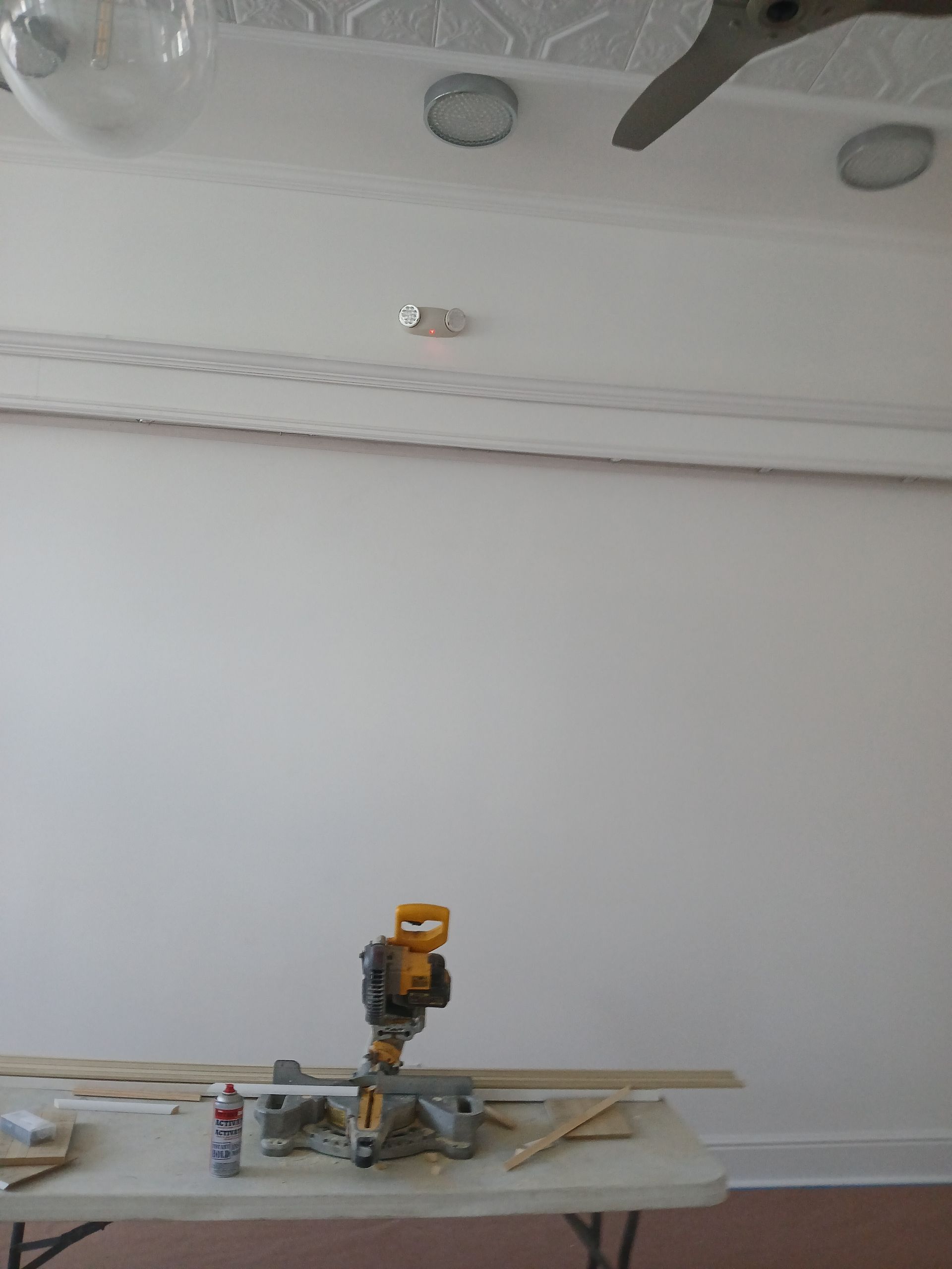 A table with a miter saw on it in front of a white wall.