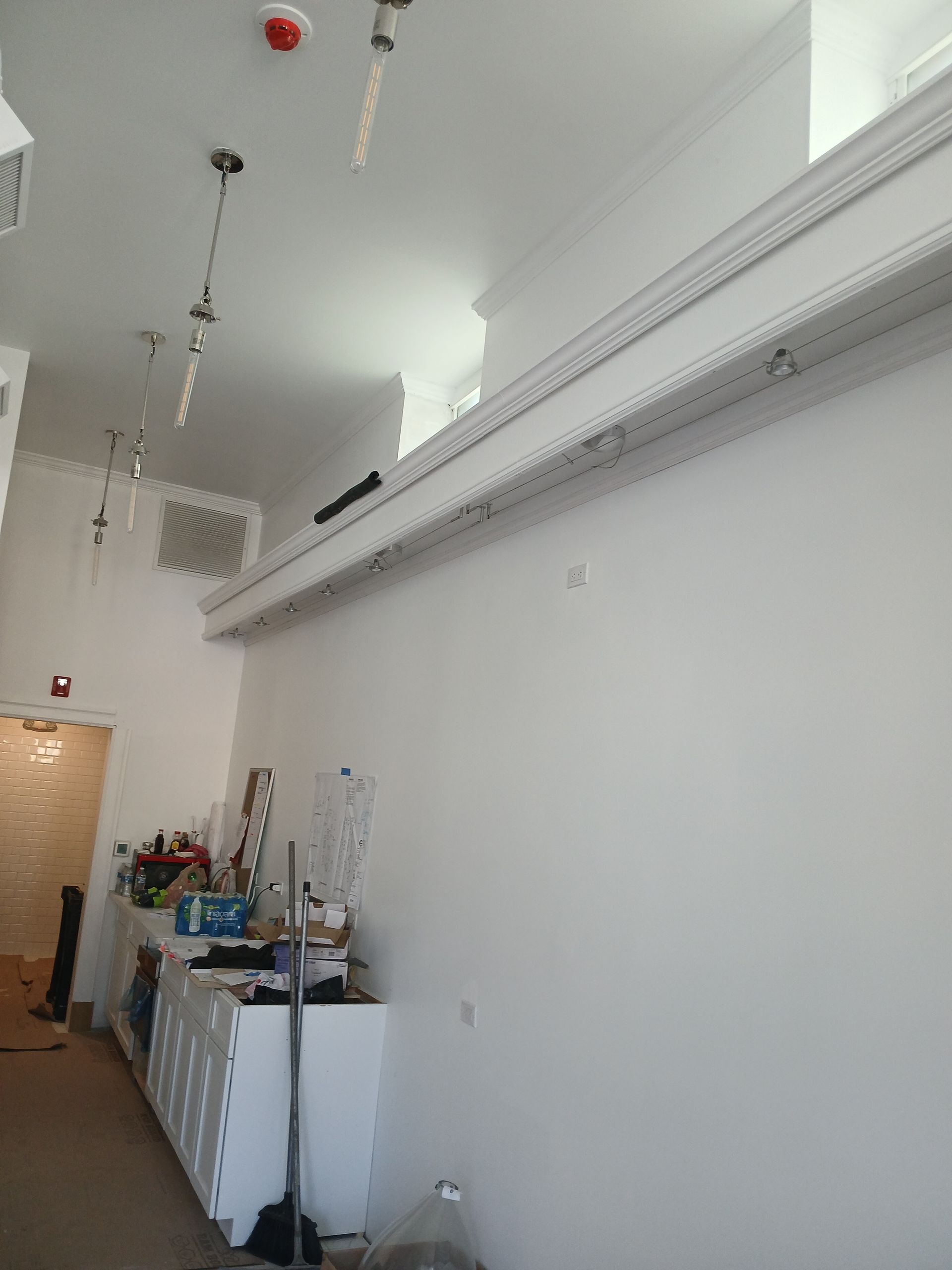 A room with white walls and a red fire alarm on the ceiling