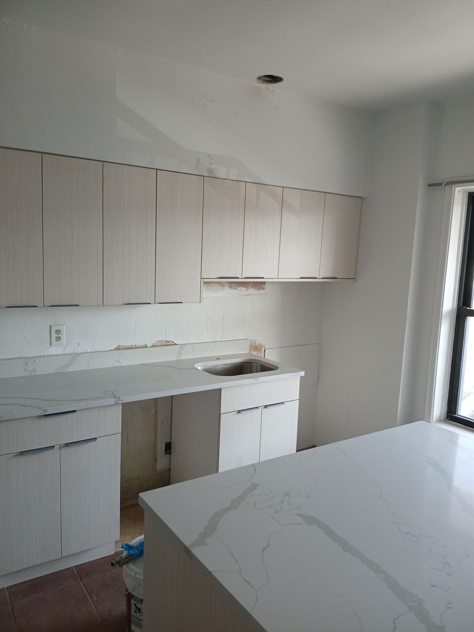 A kitchen with white cabinets and a white counter top