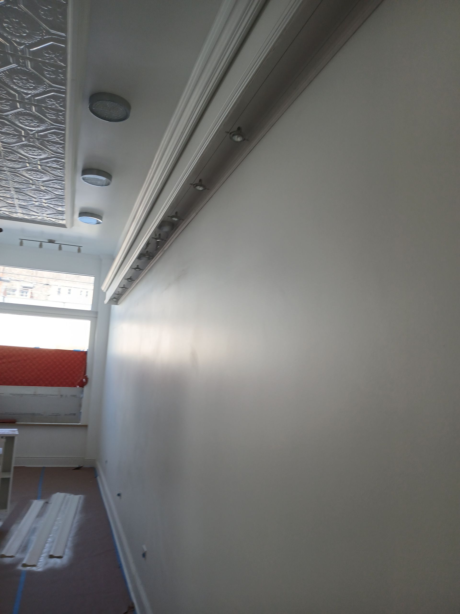 A white wall in a room with a window and a ceiling.