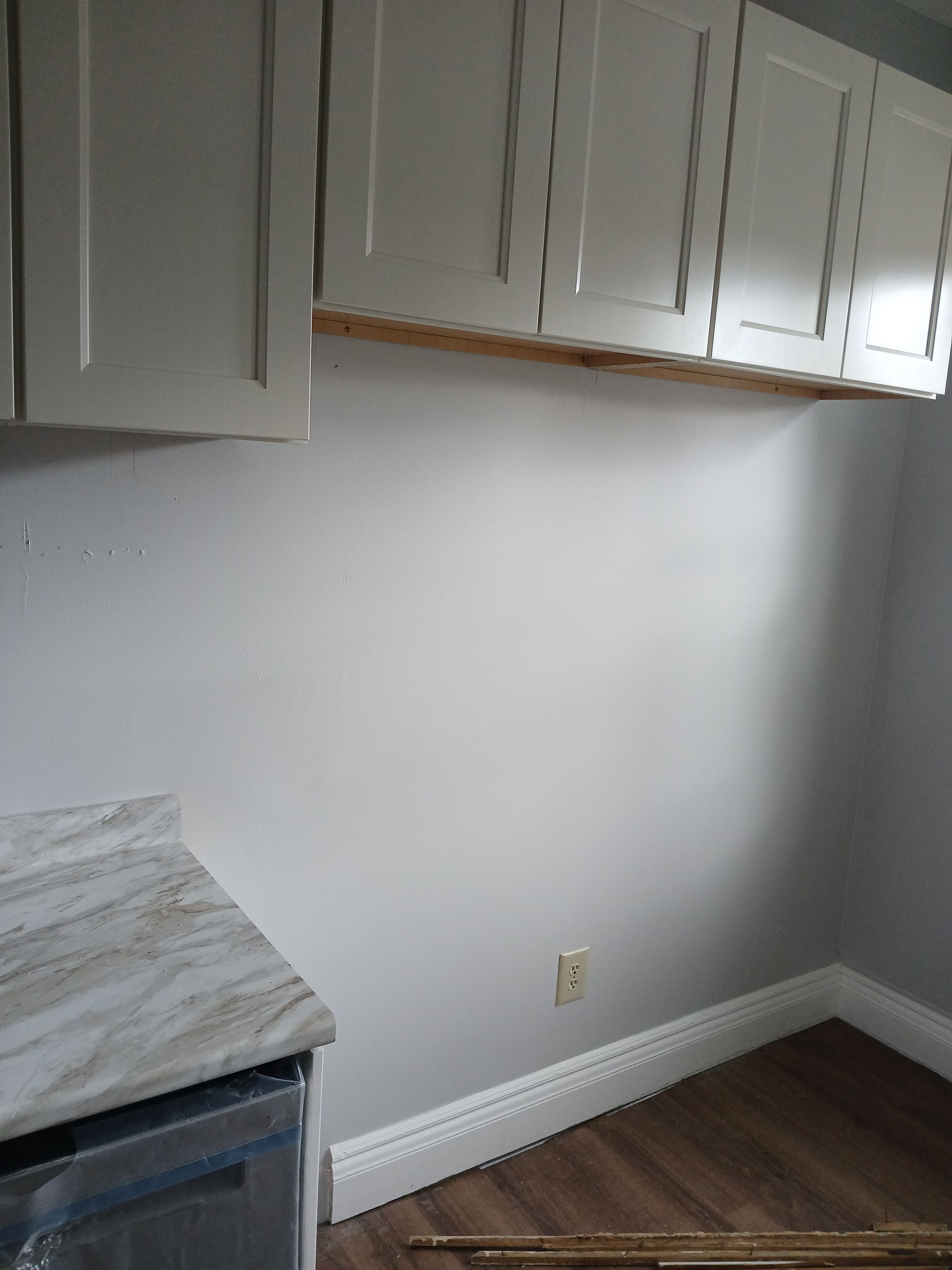 A kitchen with white cabinets and a marble counter top