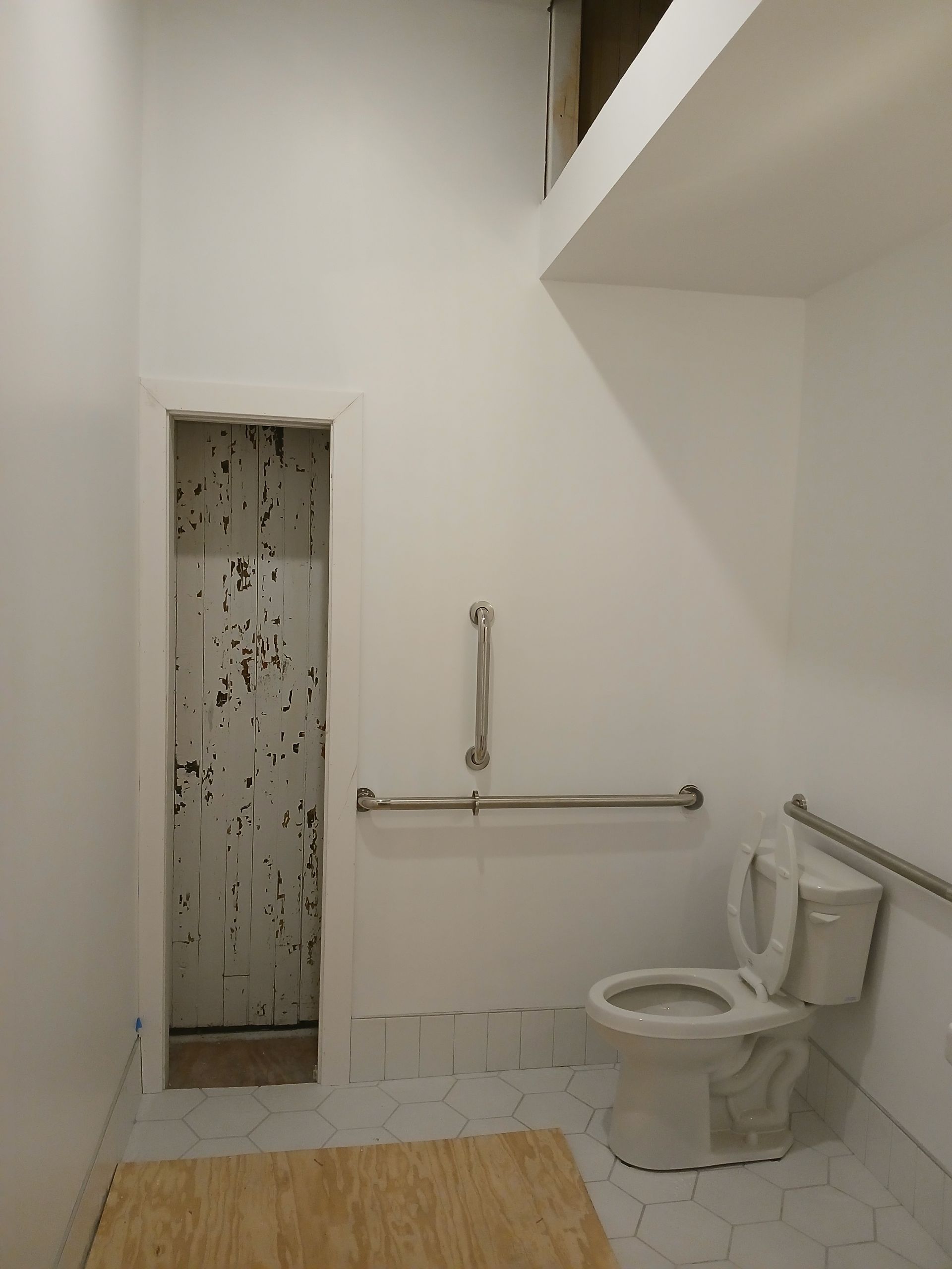 A bathroom with a toilet and a hand rail