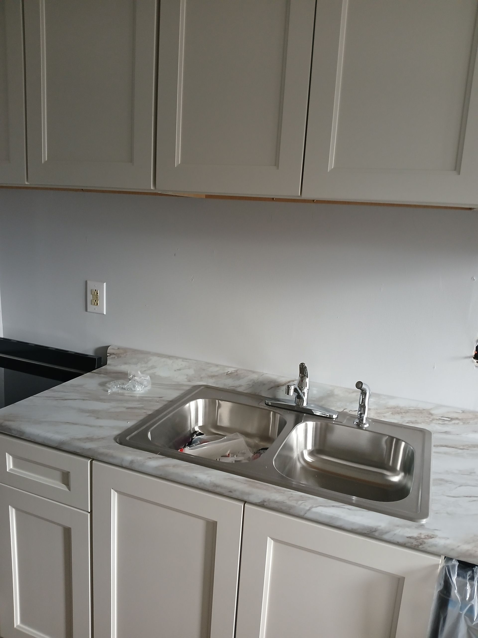 A kitchen with white cabinets and a stainless steel sink