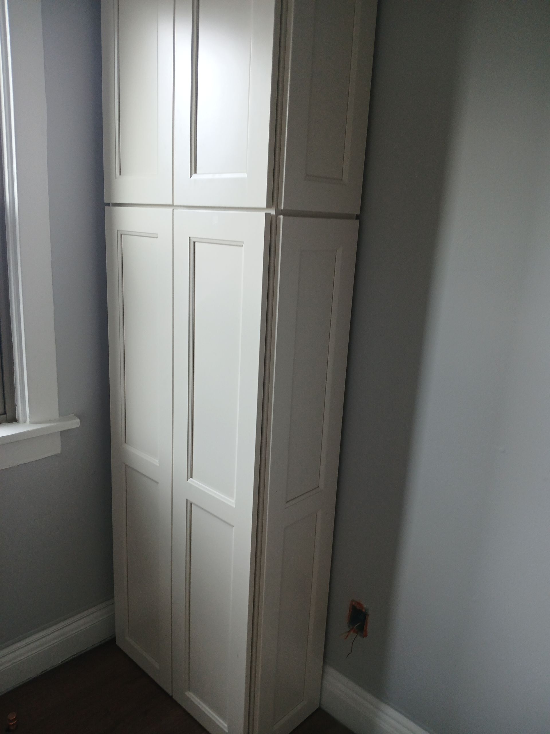 A white cabinet in a room next to a window