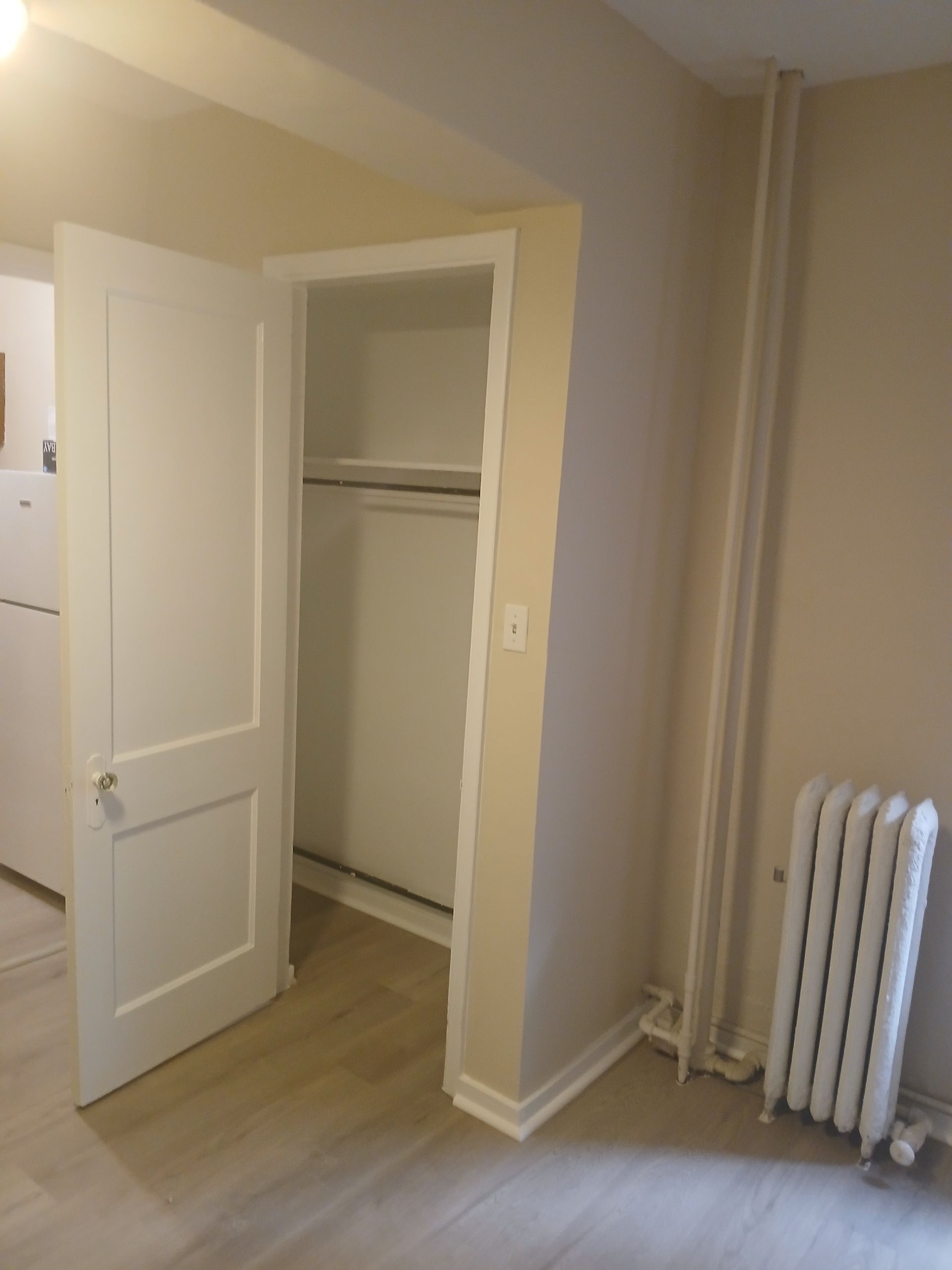 An empty room with a radiator and a closet