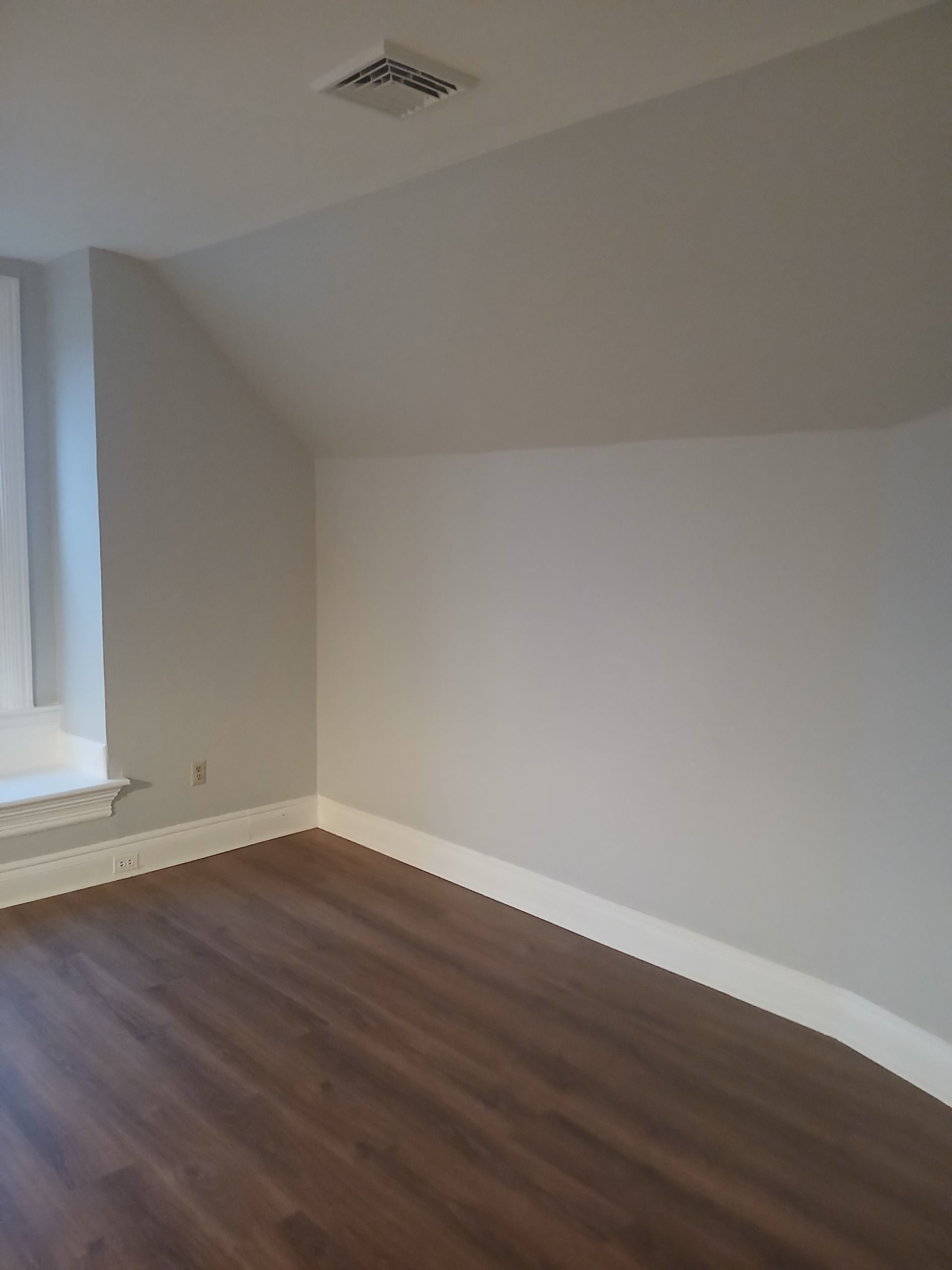 An empty room with a wooden floor and a window.