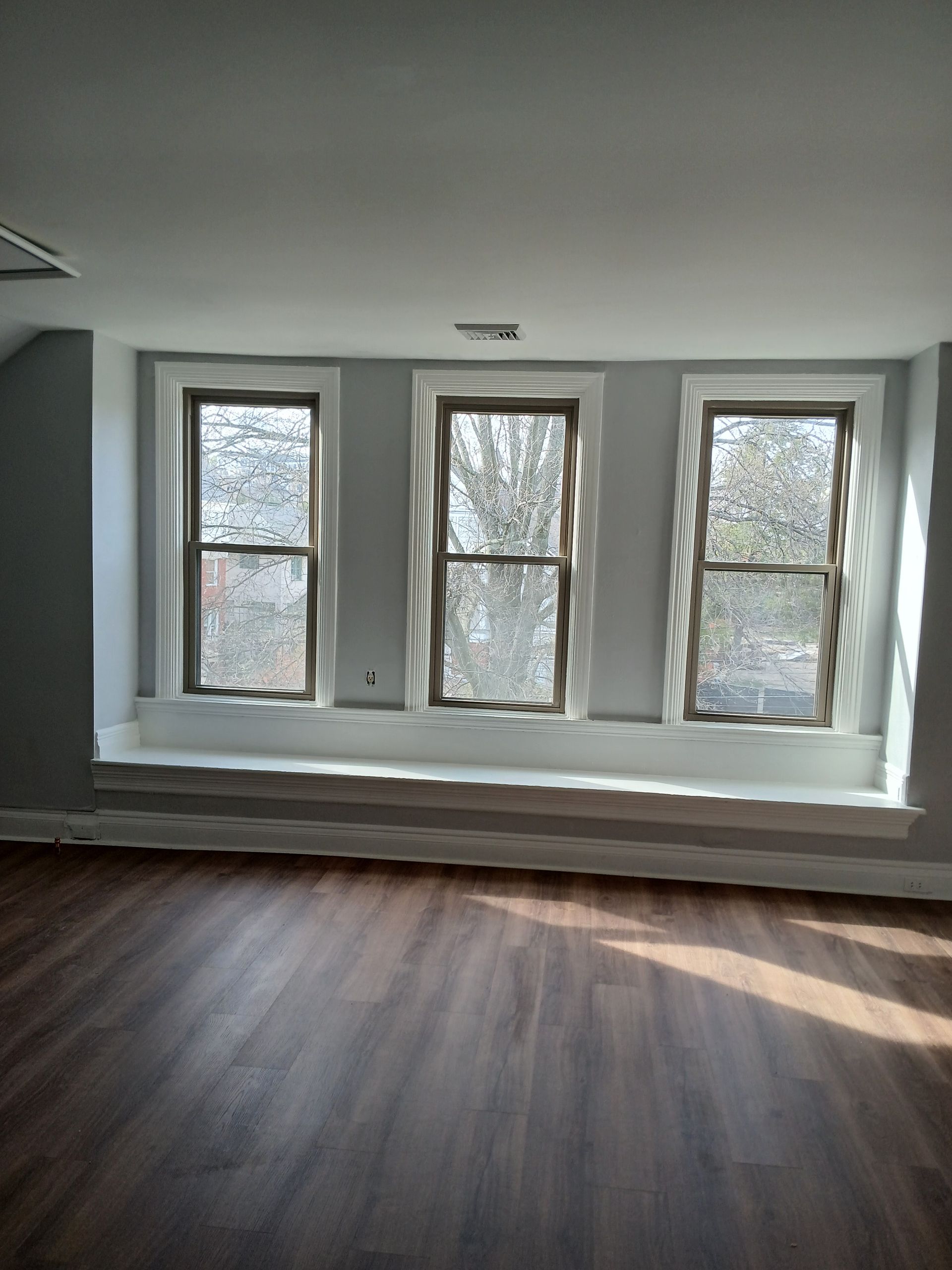 An empty room with three windows and a window seat.