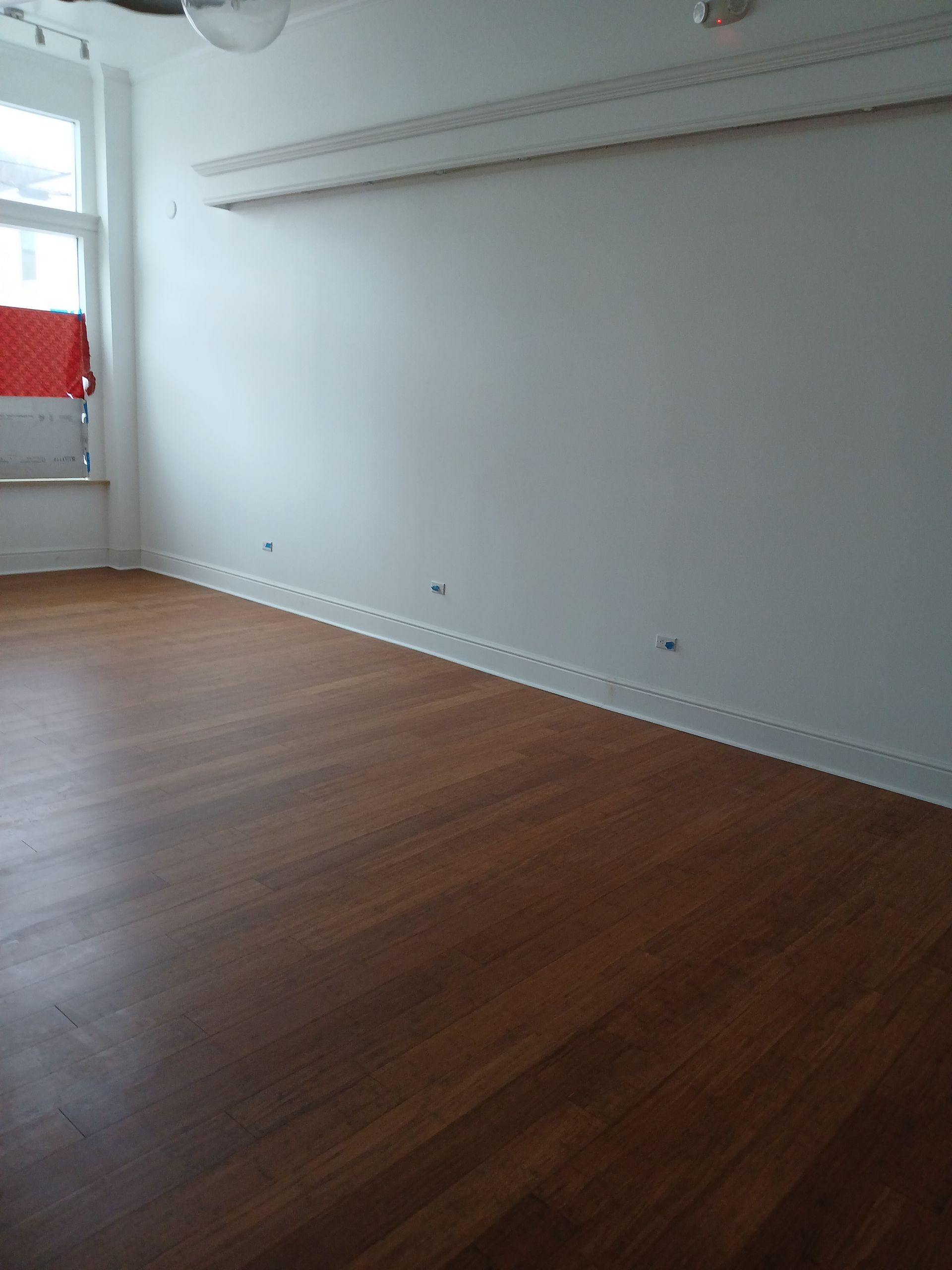 An empty room with a wooden floor and white walls