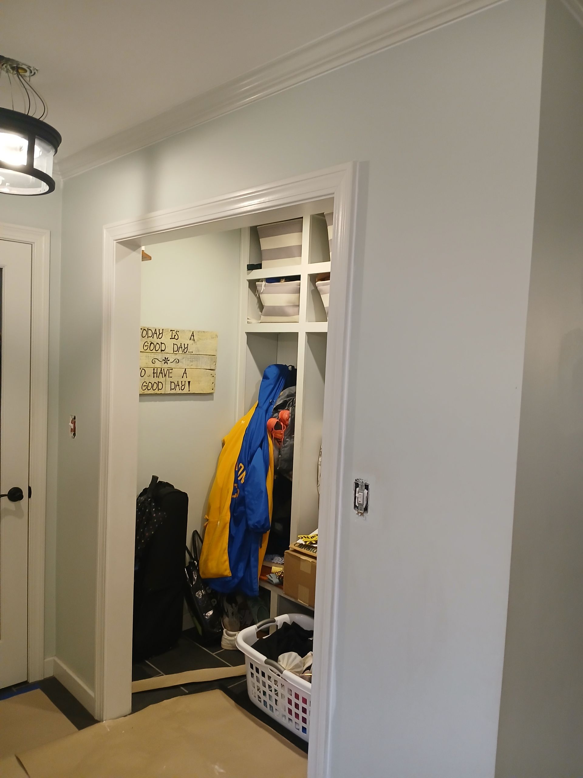 A person in a blue jacket is standing in a closet