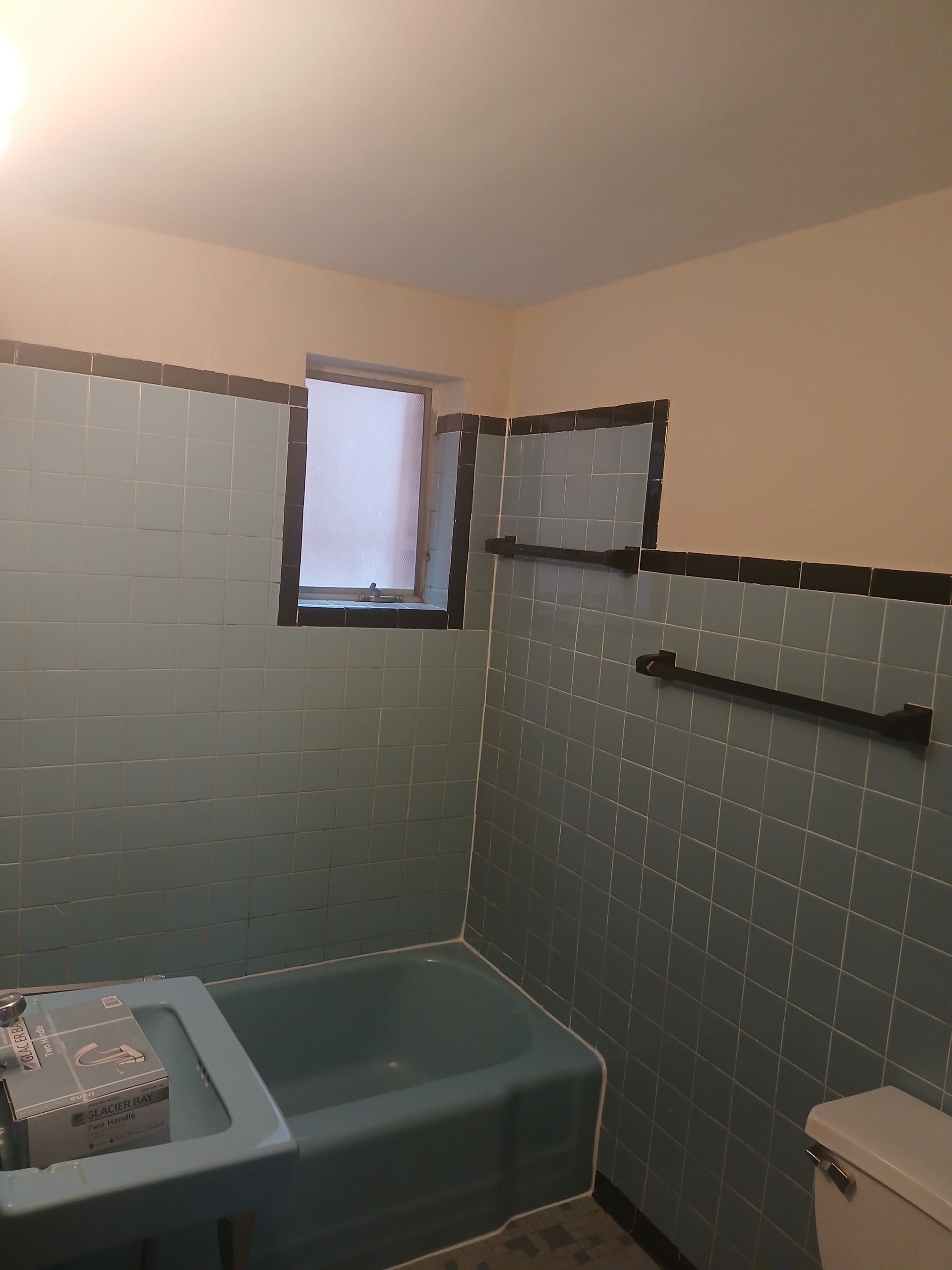 A bathroom with a tub , toilet , sink and window.