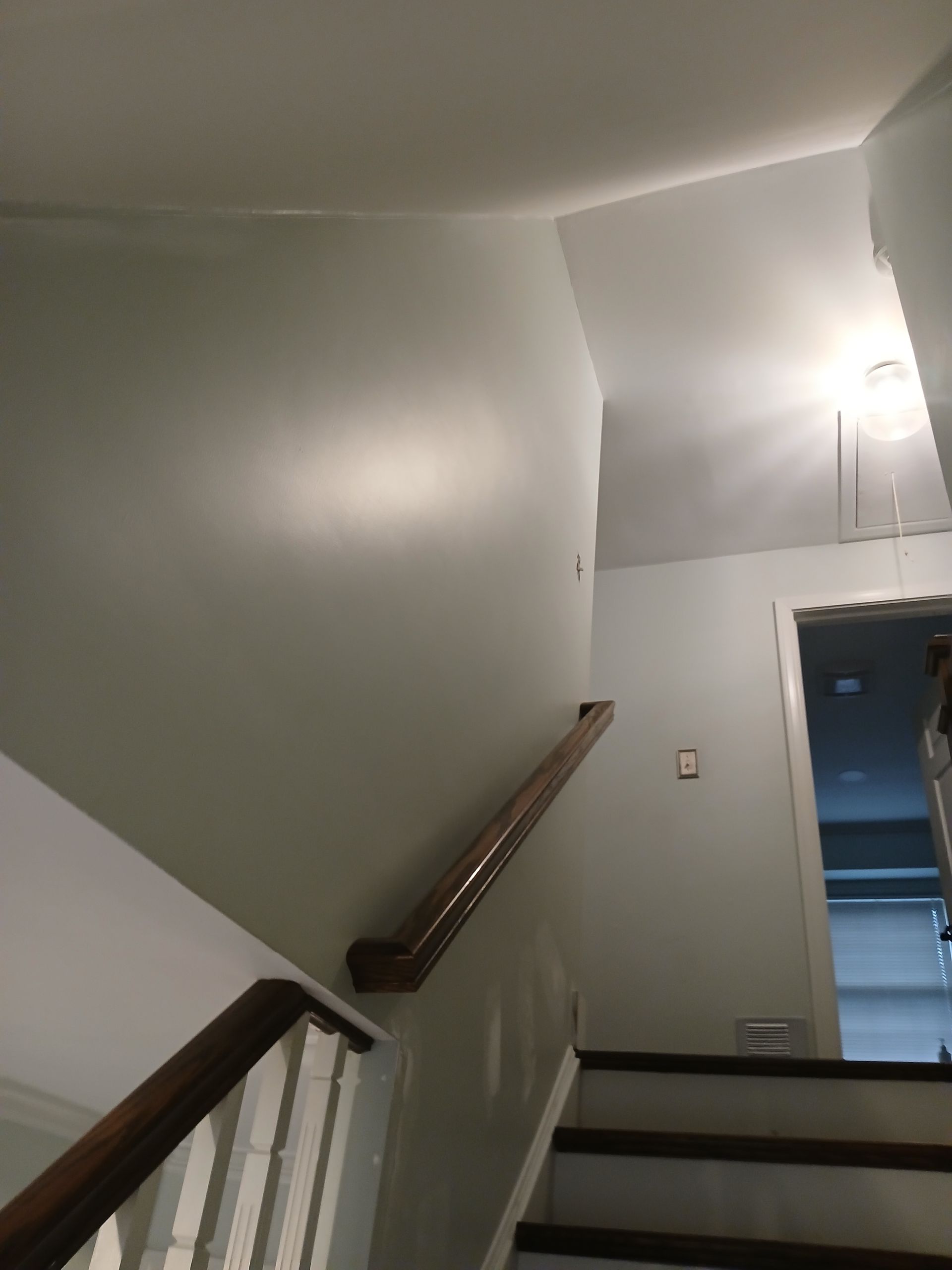 A staircase with white walls and a wooden railing