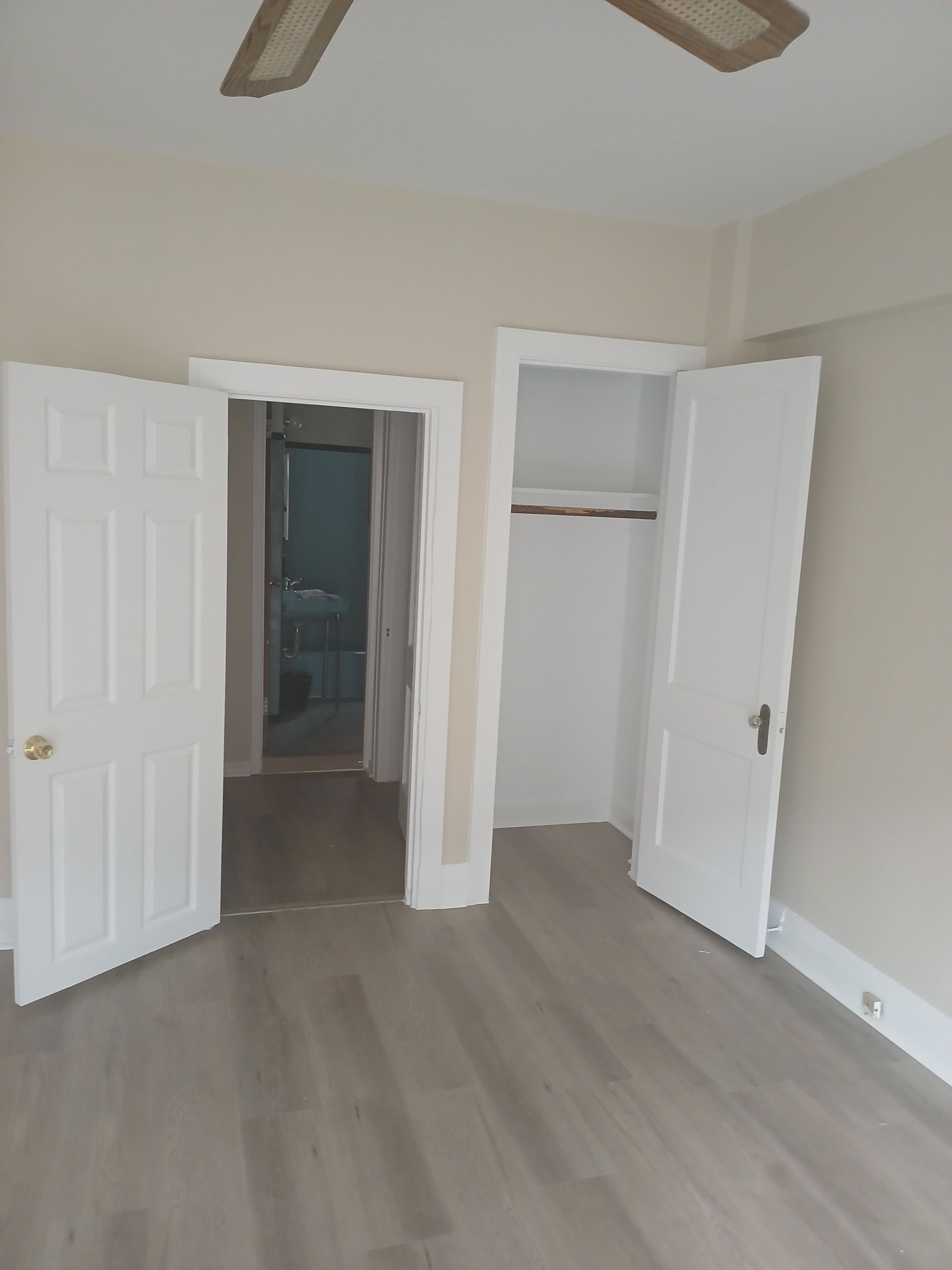 An empty room with hardwood floors and a ceiling fan.