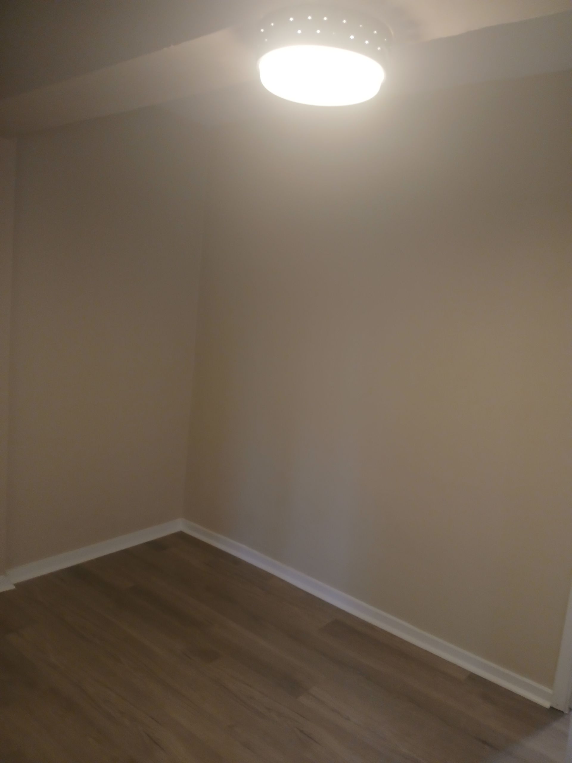 An empty room with hardwood floors and a light on the ceiling.