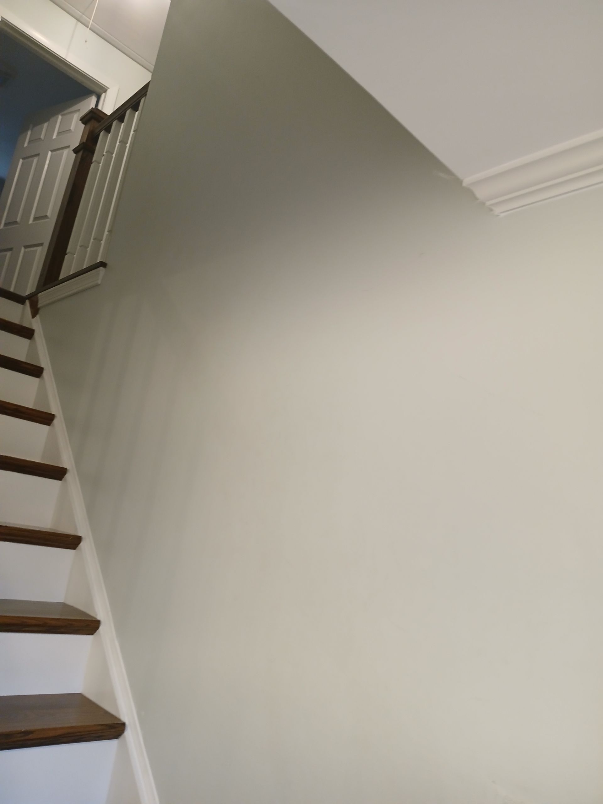 A staircase with a white wall and wooden steps