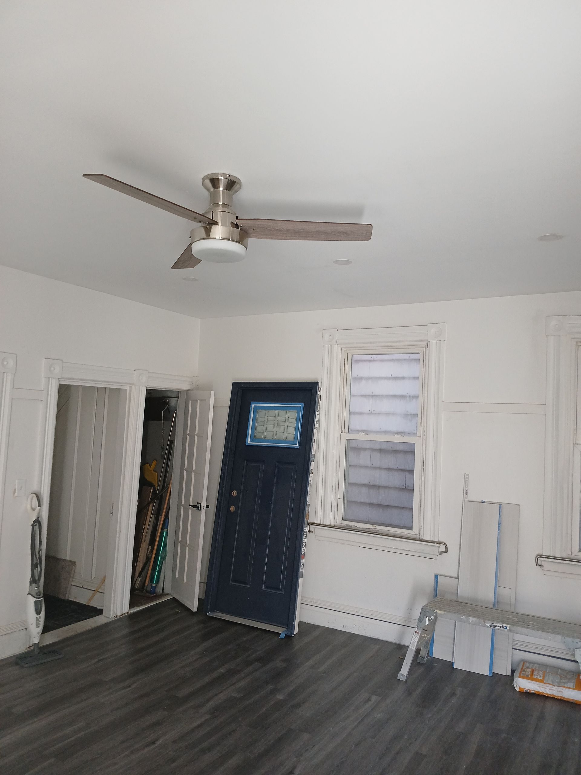 An empty room with a ceiling fan and a door