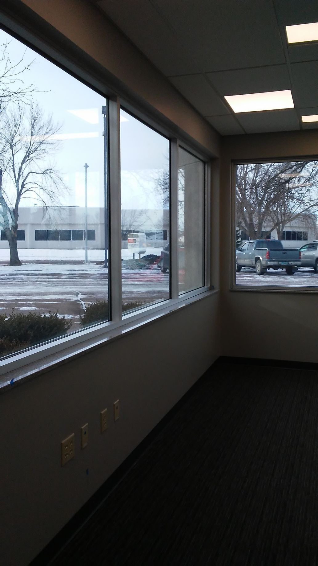 Interior corner room with windows overlooking a snow-covered street and buildings.