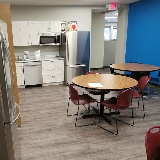 Kitchen area with cabinets, appliances, round tables, and chairs; blue accent wall.