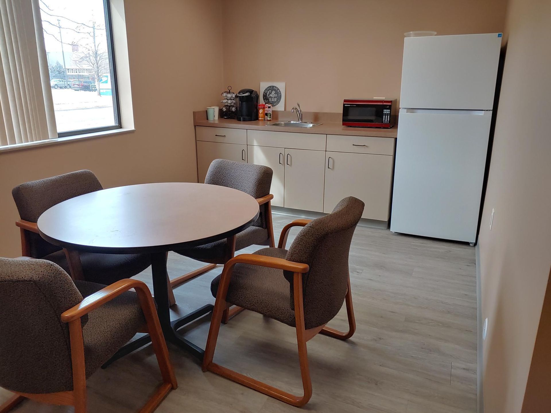 Small office break room with a table, chairs, sink, microwave, and refrigerator.