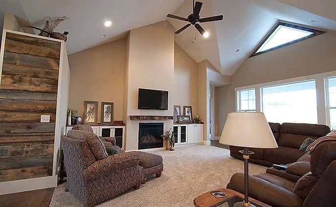 A living room with a couch , chair , lamp , television and fireplace.