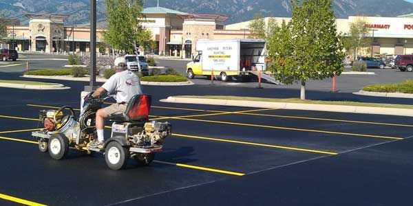 A man is riding a lawn mower in a parking lot.