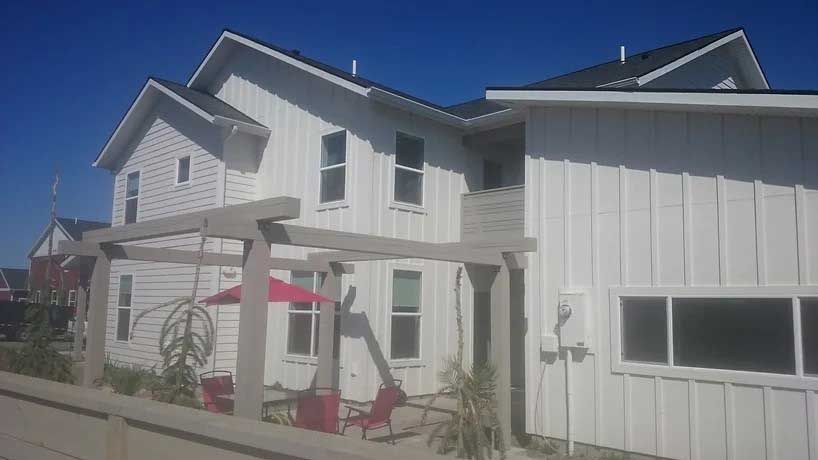 A row of white houses with red chairs and umbrellas in front of them.