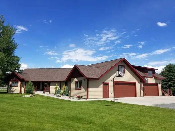 A large house with two garages and a large lawn in front of it.