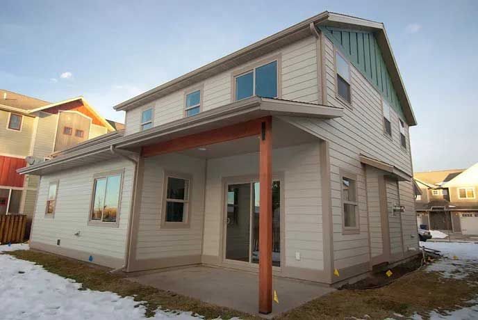 The back of a house with a porch and snow on the ground.