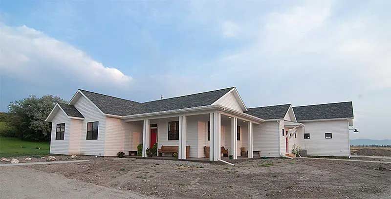 A white house with a porch and a blue sky in the background