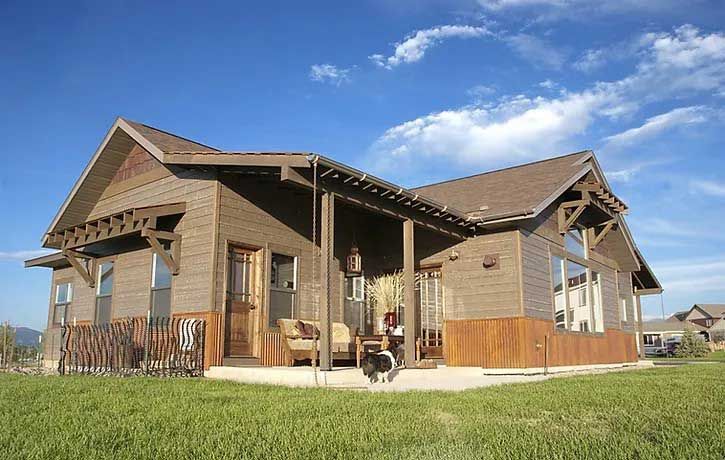 A house with a porch and a dog sitting on the porch.