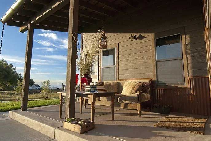 There is a porch with a table and chairs on it.