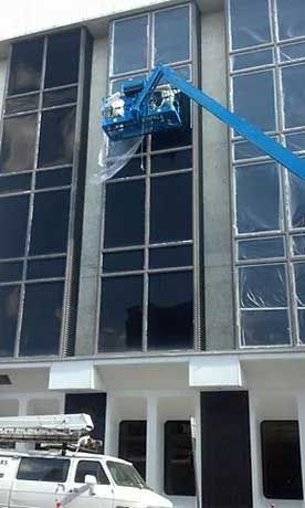 A man is cleaning the windows of a building with a crane.