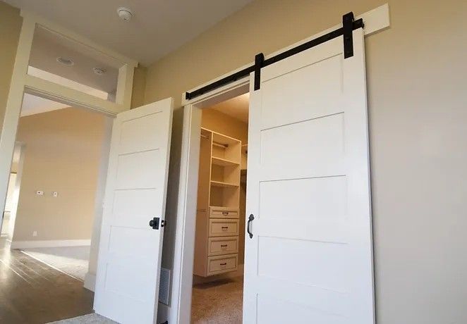 A bedroom with sliding barn doors leading to a walk in closet.