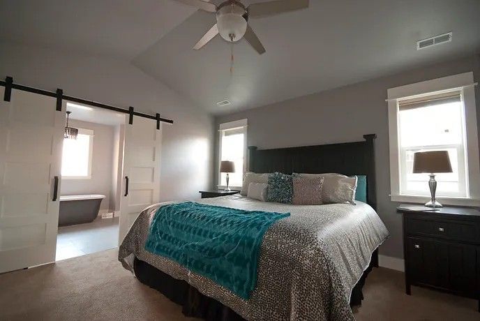 A bedroom with a king size bed and sliding barn doors leading to a bathroom.